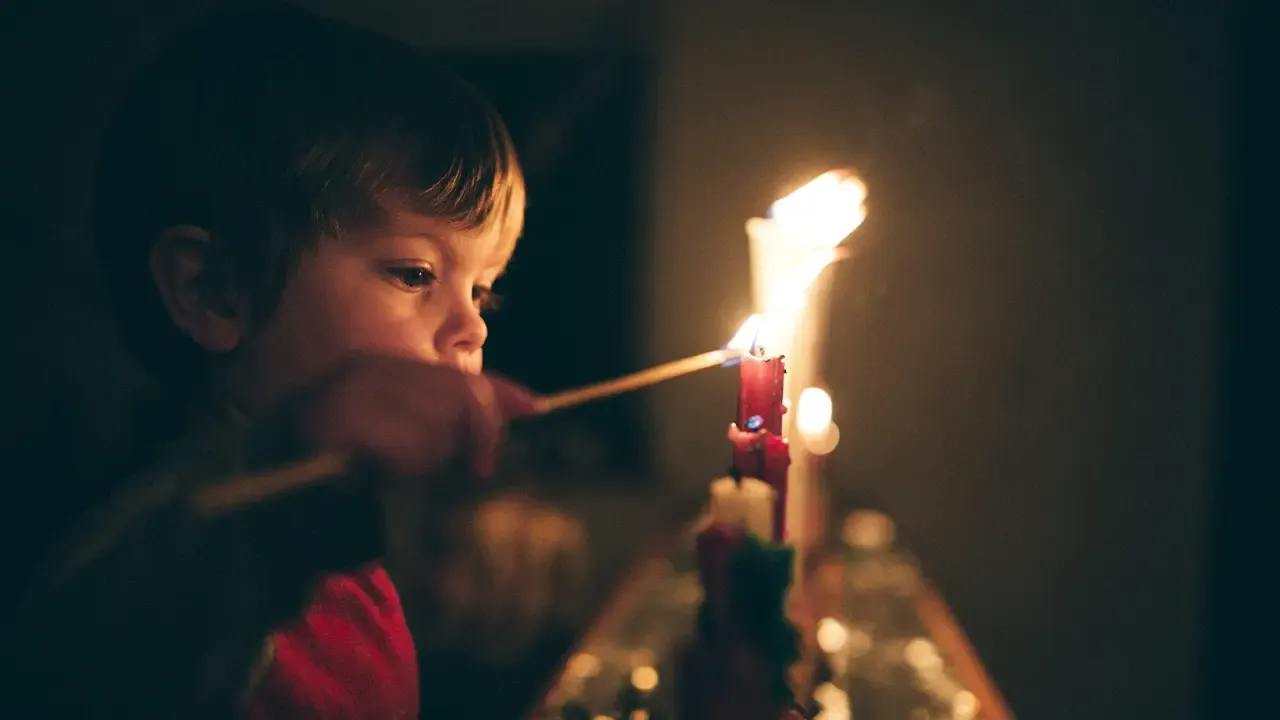 En la foto: Niño encendiendo velas