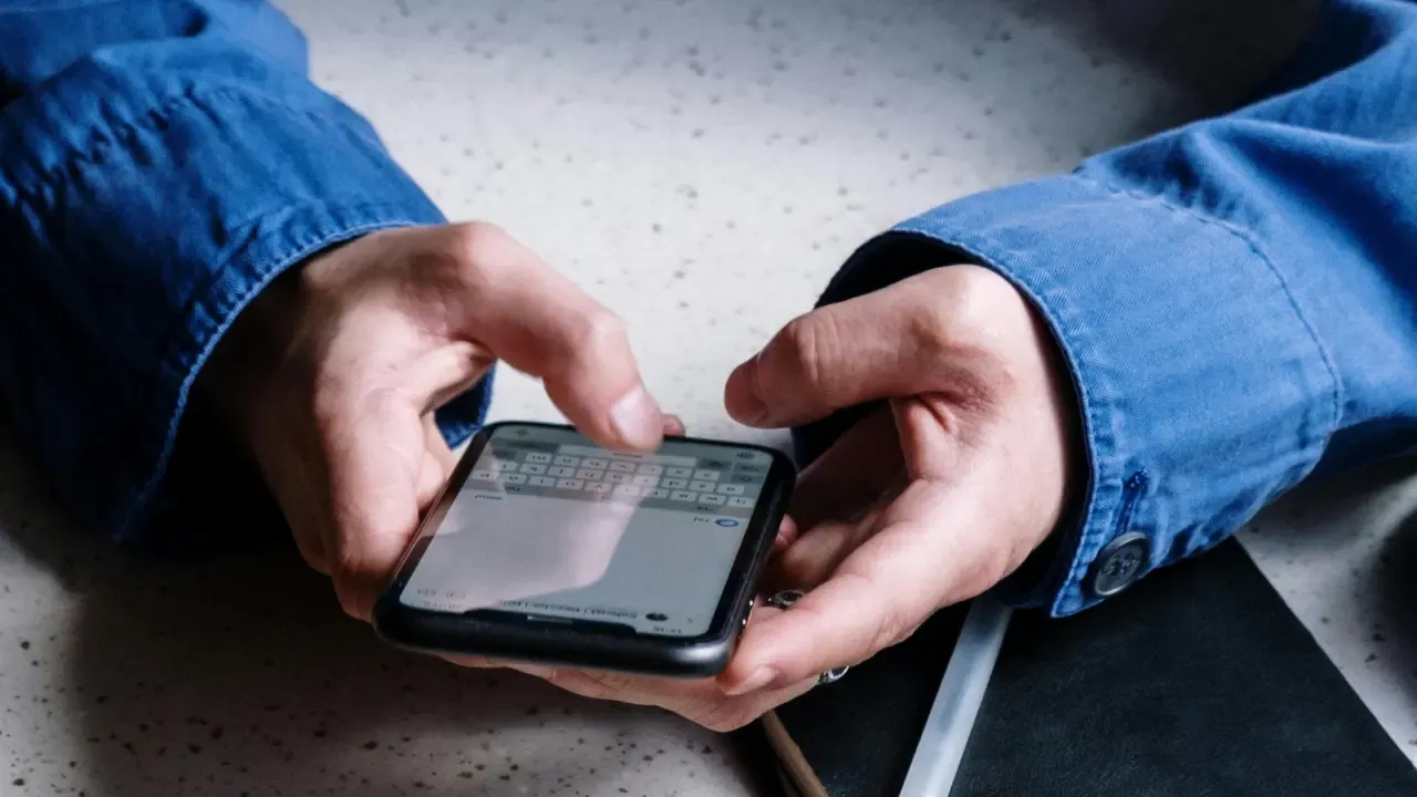 En la foto: Hombre sosteniendo celular con ambas manos
