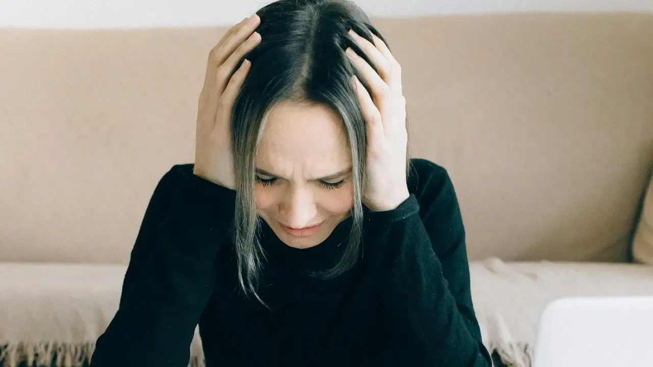 En la foto: Mujer con las manos en la cabeza expresión preocupada.
