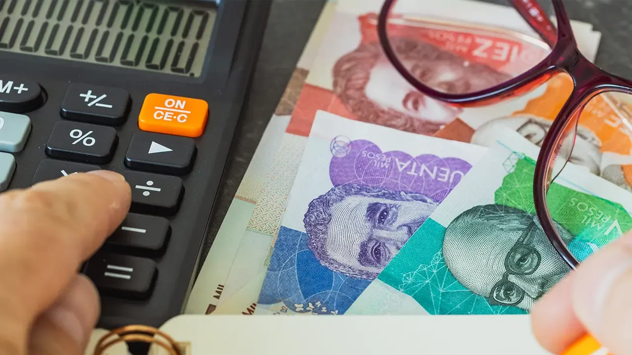 En la foto: Billetes colombianos, calculadora y lentes.