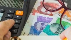En la foto: Billetes colombianos, calculadora y lentes.