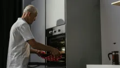 En la foto: Señor de edad cocinando en horno de cocina